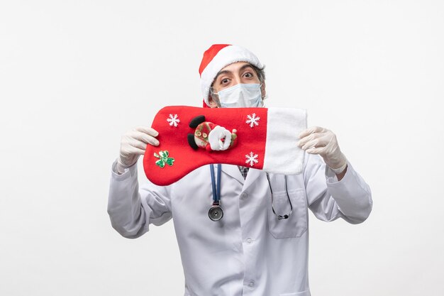 Free photo front view male doctor with big holiday sock on the white wall covid- christmas virus