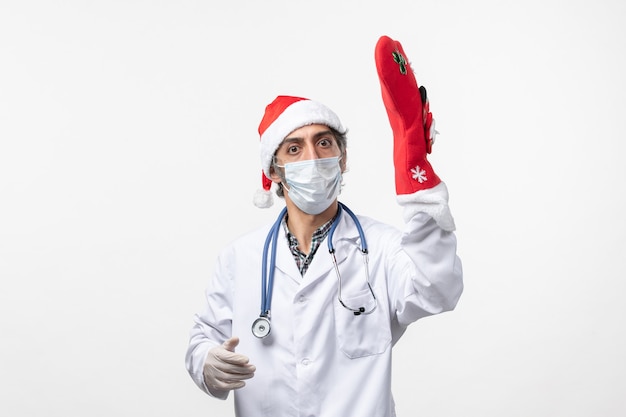 Front view male doctor with big red sock on white wall virus covid- christmas holiday