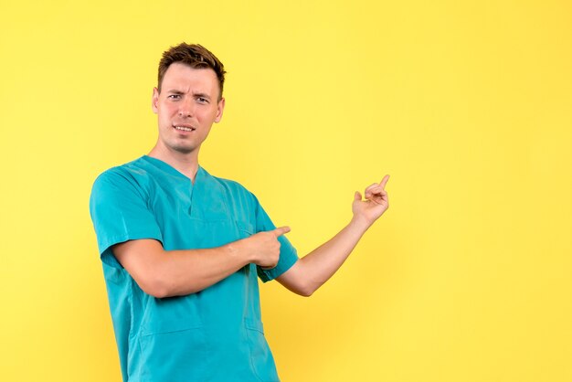 Front view of male doctor with confused expression on yellow wall
