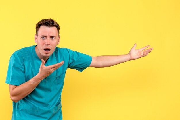 Front view of male doctor with confused expression on yellow wall