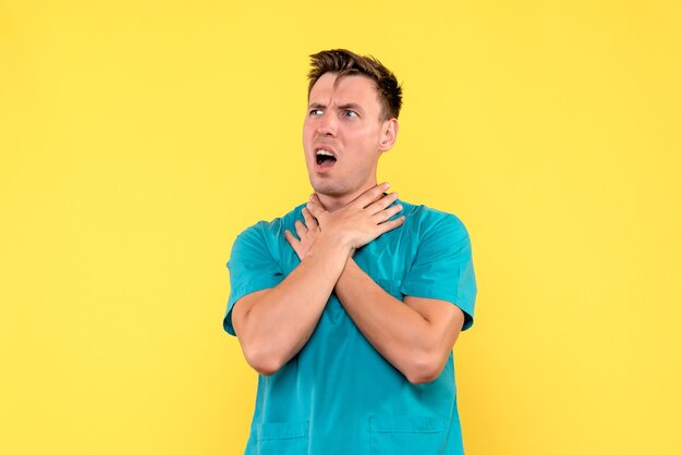 Front view of male doctor with confused face on yellow wall