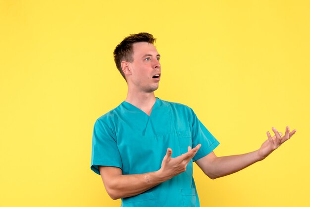 Front view of male doctor with confused face on yellow wall