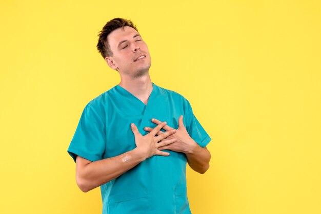 Front view of male doctor with delighted face on yellow wall