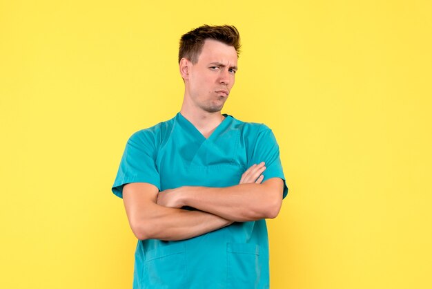 Front view of male doctor with displeased expression on yellow wall