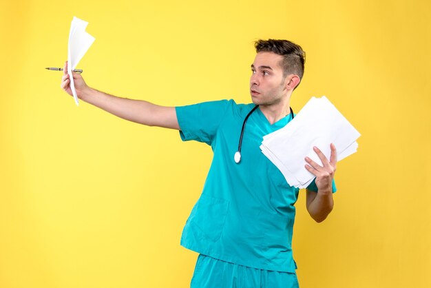 Front view of male doctor with documents on a yellow wall