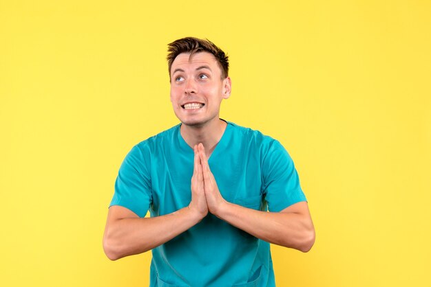 Front view of male doctor with excited expression on yellow wall