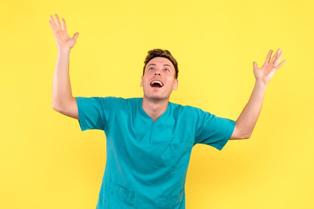 Front view of male doctor with excited expression on yellow wall