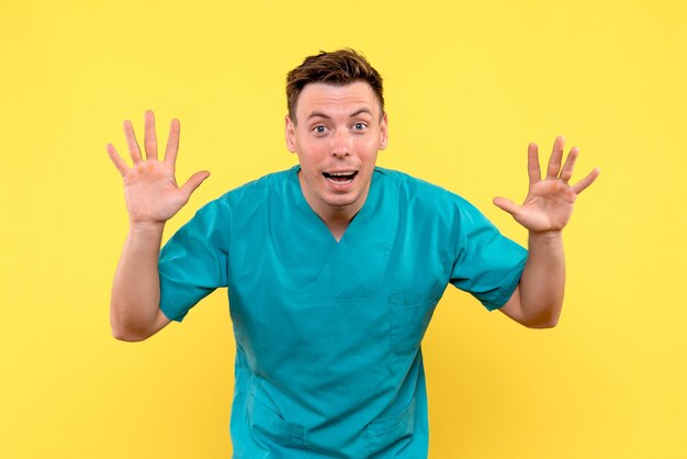Front view of male doctor with excited expression on yellow wall