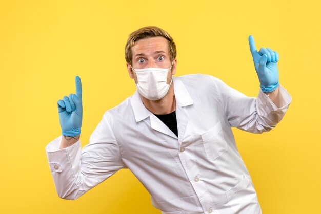 Вид спереди мужчина-врач с возбужденным лицом на желтом фоне пандемический медик covid- здоровье