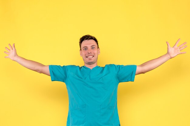 Вид спереди мужчины-врача с возбужденным лицом на желтой стене