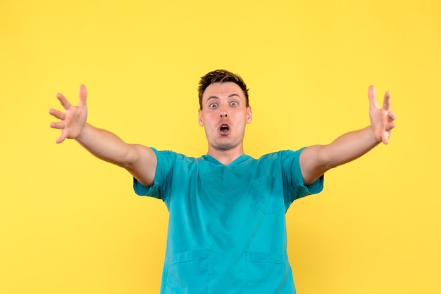 Front view of male doctor with excited face on yellow wall