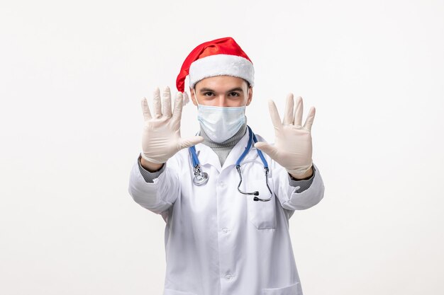 Front view of male doctor with gloves and mask on white wall