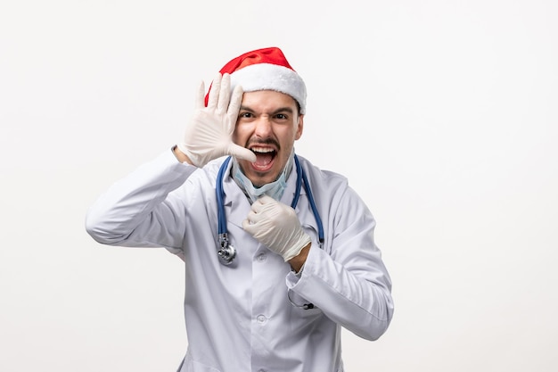 Vista frontale del medico maschio con guanti e maschera sul muro bianco