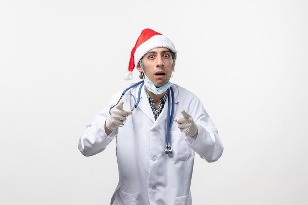 Front view male doctor with gloves on a white wall virus holiday covid- emotion