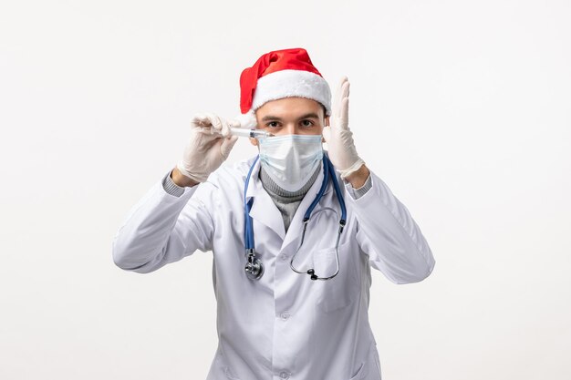 Front view of male doctor with injection on white wall