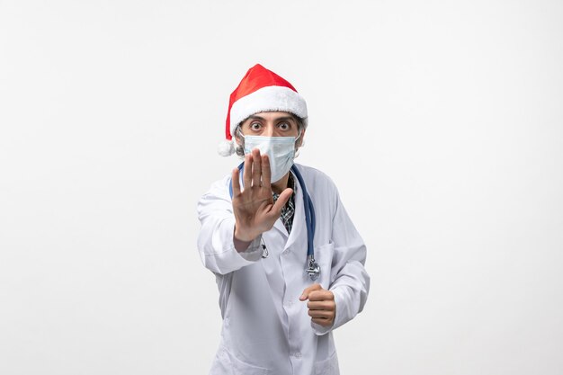 Вид спереди мужчина-врач с маской на белой стене праздник пандемического вируса covid
