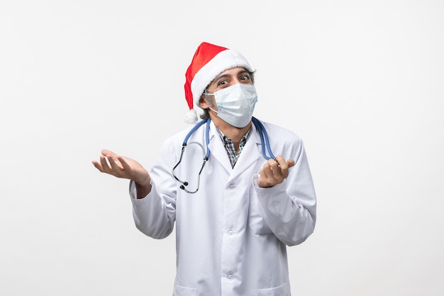 Front view male doctor with mask on a white wall pandemic covid holiday virus