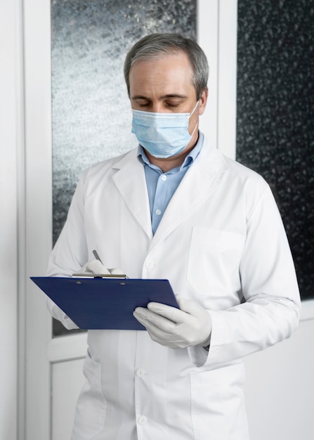 Free photo front view of male doctor with medical mask and notepad preparing for patients vaccinations