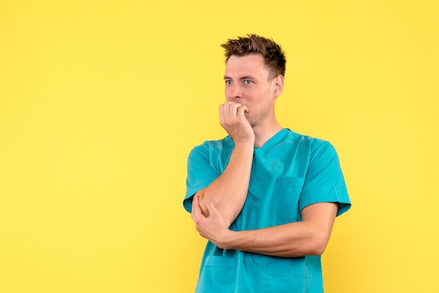 Front view of male doctor with nervous expression on yellow wall