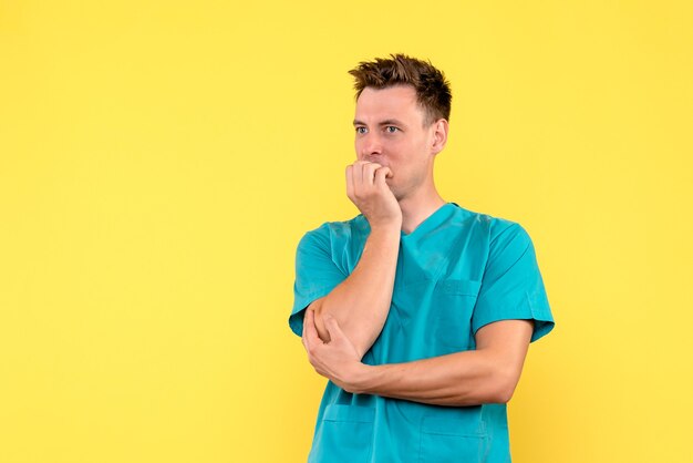 Вид спереди мужчины-врача с нервным выражением лица на желтой стене