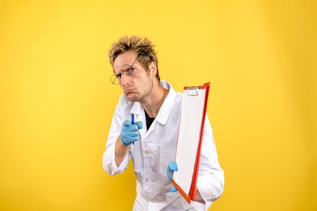 Front view male doctor with notes on a yellow background health human covid medic