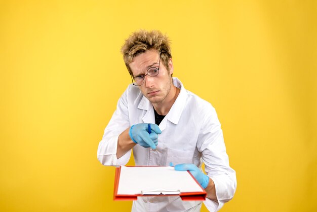 Вид спереди мужской врач с заметками на желтом фоне здоровья человека covid medic