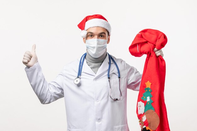 Front view of male doctor with present bag on the white wall