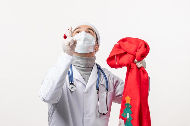 Front view of male doctor with present bag on white wall