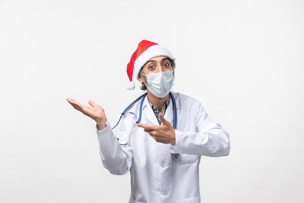 Medico maschio di vista frontale con cappuccio rosso e maschera sulla pandemia covid del nuovo anno della parete bianca