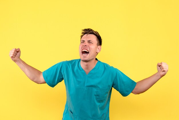 Front view of male doctor with rejoicing expression on yellow wall