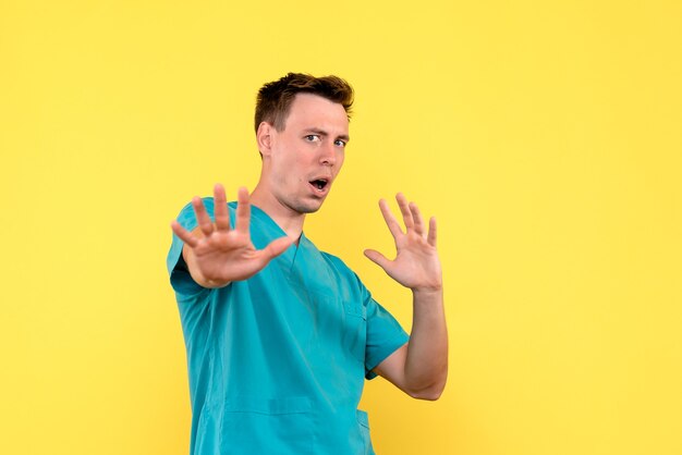 Front view of male doctor with scared expression on yellow wall