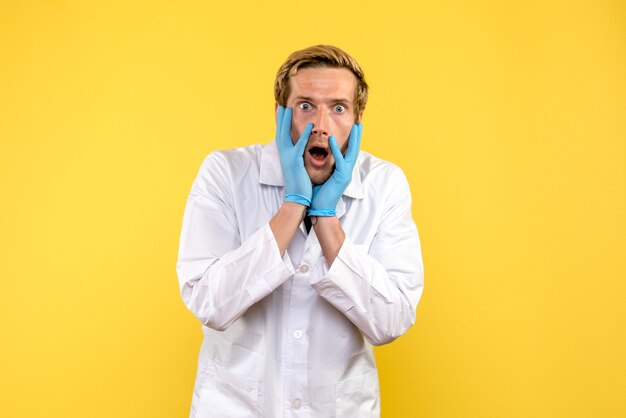 Front view male doctor with scared face on yellow background medic health covid pandemic