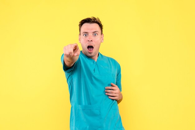 Front view of male doctor with shocked expression on yellow wall