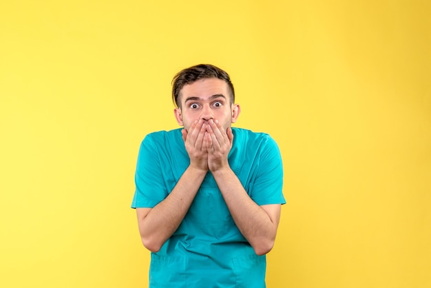 Front view of male doctor with shocked face on yellow wall