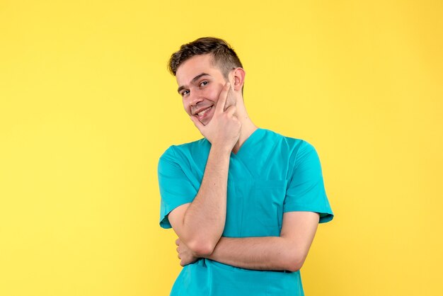 Front view of male doctor with smile on yellow wall