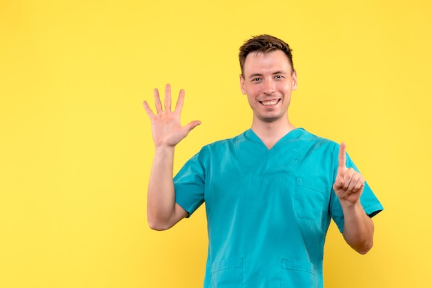 Front view of male doctor with smiling expression on yellow wall