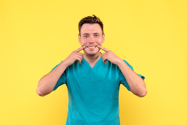 Front view of male doctor with smiling expression on yellow wall