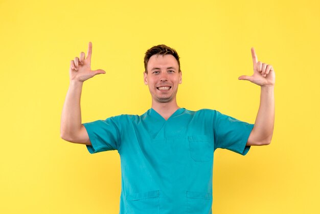 Front view of male doctor with smiling face on a yellow wall