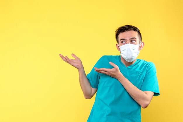 Вид спереди мужчины-врача со стерильной маской на светло-желтой стене