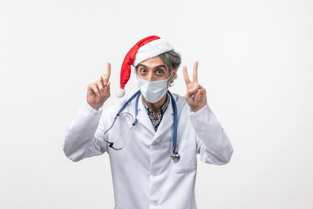 Front view male doctor with sterile mask on a white wall new year covid virus pandemic