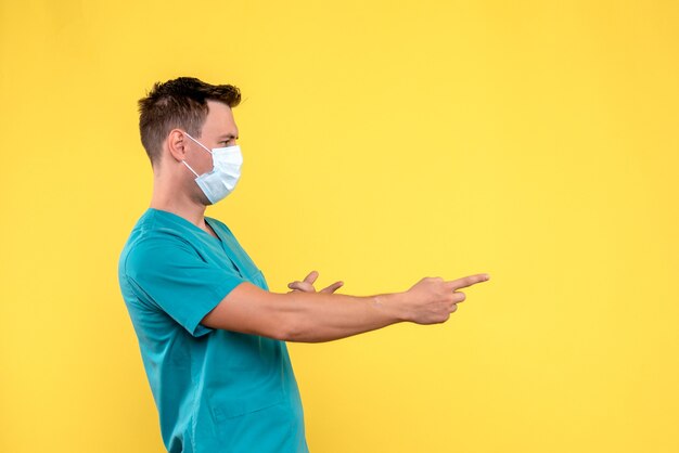 黄色の壁に滅菌マスクと男性医師の正面図
