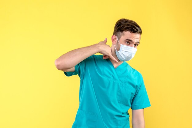 Front view of male doctor with sterile mask on yellow wall