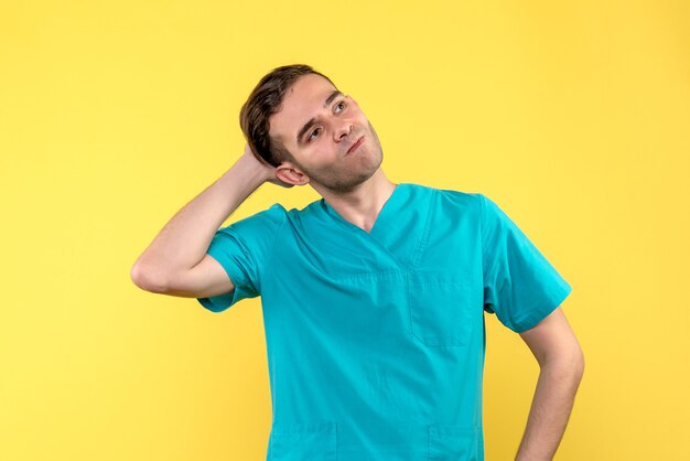 Front view of male doctor with stressed face on yellow wall