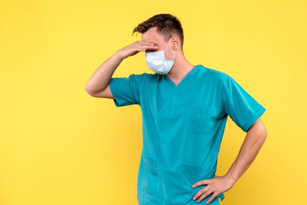 Front view of male doctor with stressful expression on yellow wall