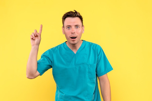 Front view of male doctor with surprised expression on a yellow wall