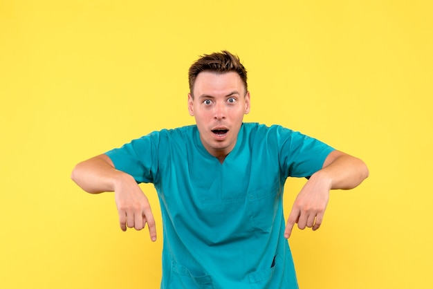 Front view of male doctor with surprised expression on yellow wall