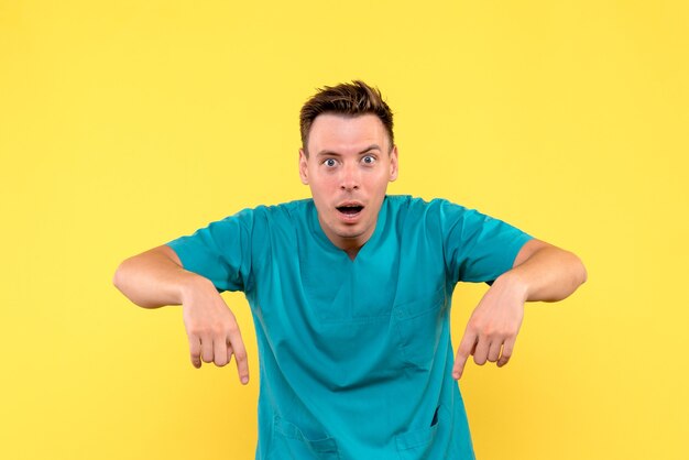 Front view of male doctor with surprised expression on yellow wall