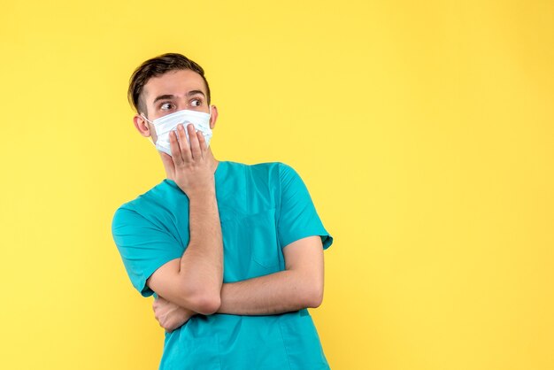 Front view of male doctor with surprised face on yellow wall