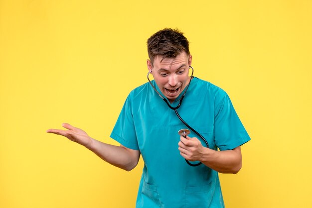 Front view of male doctor with tonometer on yellow wall