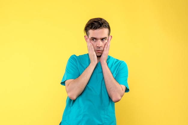 Front view of male doctor worried on yellow wall